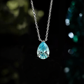 LAVEELLE Azure blue pear-cut pendant necklace on a dark bokeh background